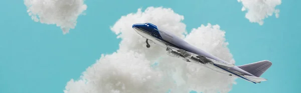 Avião de brinquedo voando entre nuvens brancas fofas feitas de lã de algodão isolado em azul, tiro panorâmico — Fotografia de Stock