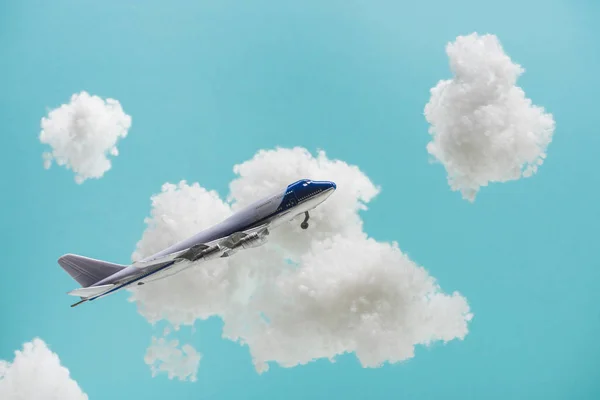 Jouet avion volant parmi les nuages duveteux blancs en laine de coton isolé sur bleu — Photo de stock