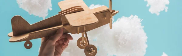 Avião de brinquedo de madeira voando entre nuvens brancas fofas feitas de lã de algodão isolado em azul, tiro panorâmico — Fotografia de Stock