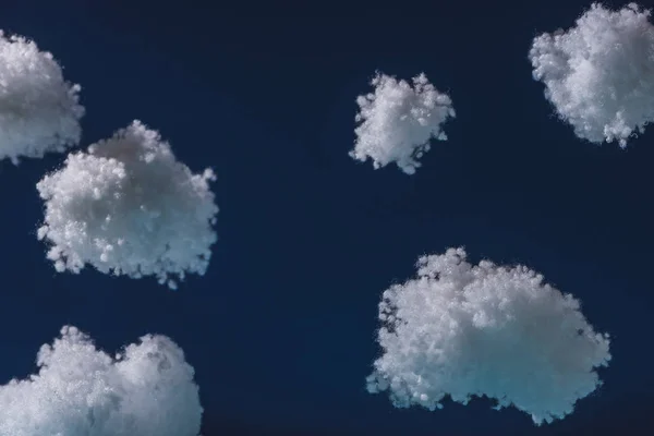 Nuvens fofas brancas feitas de lã de algodão isolada em azul escuro — Fotografia de Stock