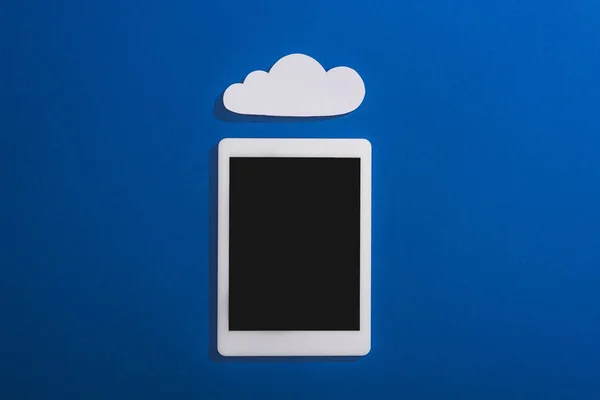 Вид зверху порожня біла паперова хмара біля цифрового планшета з порожнім екраном на синьому — стокове фото
