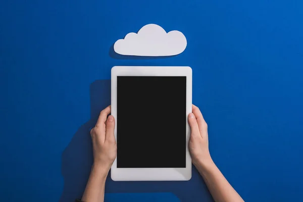 Cropped view of woman holding digital tablet near empty white paper cloud on blue — Stock Photo