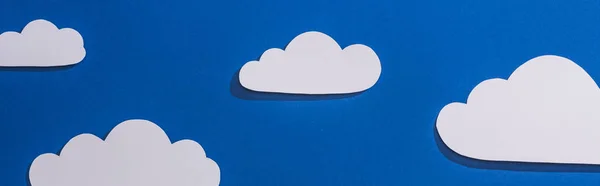 Top view of white paper cut clouds on blue background, panoramic shot — Stock Photo