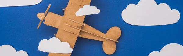 Draufsicht auf Holzflugzeug in blauem Himmel mit papiergeschnittenen weißen Wolken, Panoramaaufnahme — Stockfoto