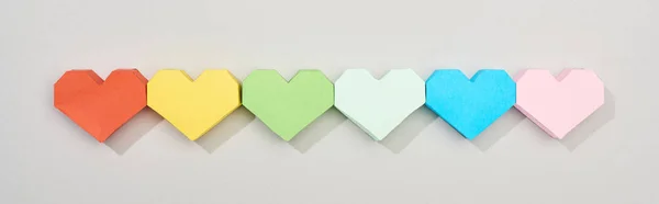 Vista superior de corações de papel coloridos em fundo cinza, tiro panorâmico — Fotografia de Stock