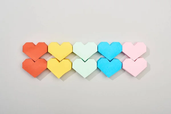 Верхний вид цветных бумажных сердец на сером фоне — стоковое фото