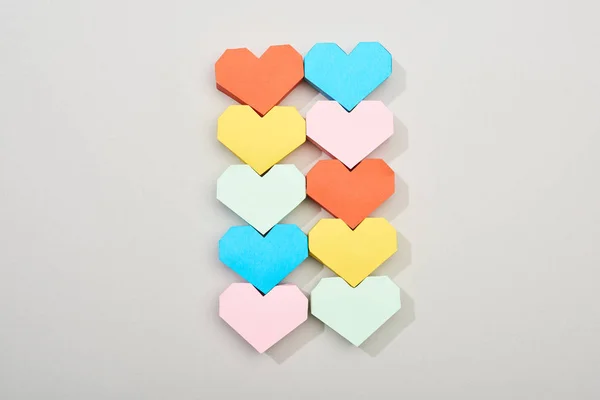Vue du dessus des papiers colorés en forme de coeur sur fond gris — Photo de stock