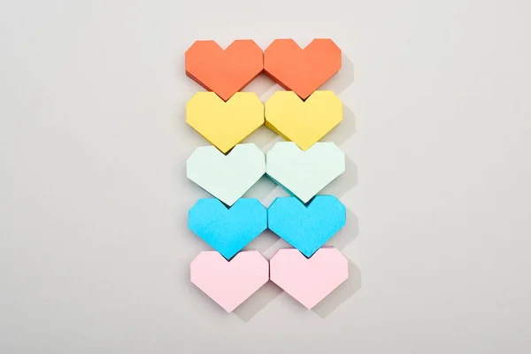 Vista superior de coloridos papeles en forma de corazón sobre fondo gris - foto de stock