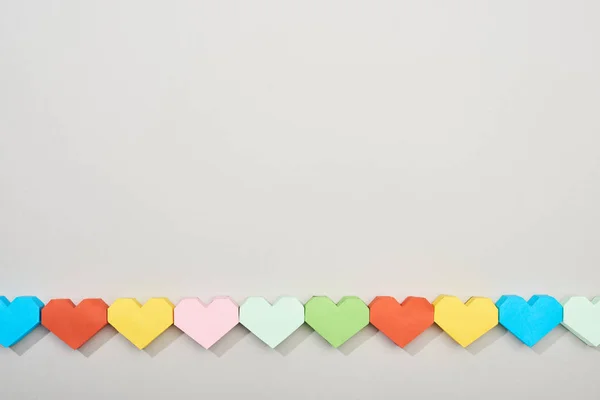 Vista superior de papeles decorativos en forma de corazón sobre fondo gris con espacio para copiar - foto de stock