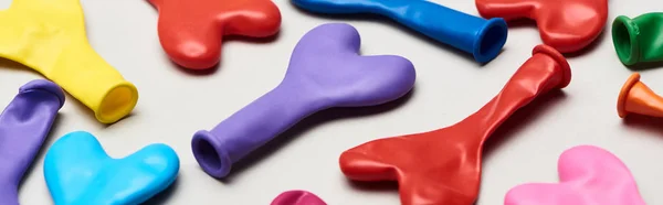 Tiro panorâmico de balões coloridos em forma de coração no fundo cinza — Fotografia de Stock
