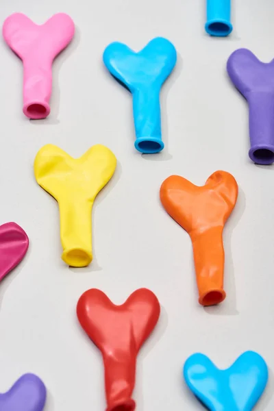 Vista superior de globos de colores en forma de corazón sobre fondo gris - foto de stock