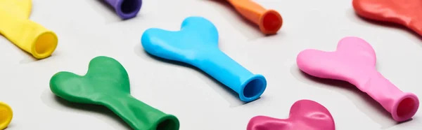 Panoramic shot of colorful rubber balloons on grey background — Stock Photo