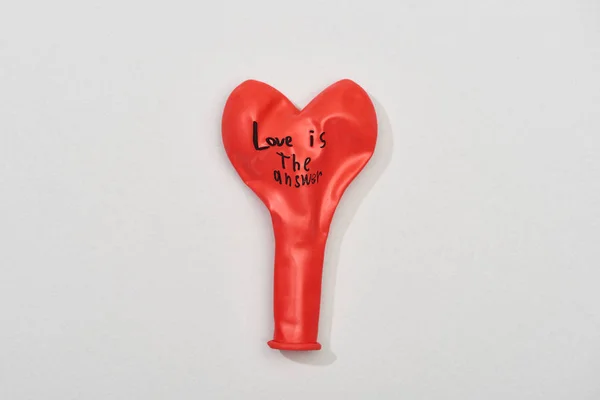 Top view of red balloon with love is answer quote on grey background — Stock Photo