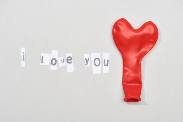 Top view of i love you lettering with red balloon on grey background — Stock Photo