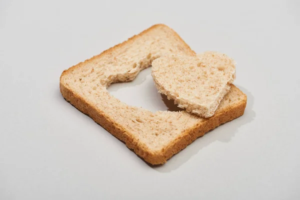Кусок хлеба с резной формой сердца на сером фоне — стоковое фото