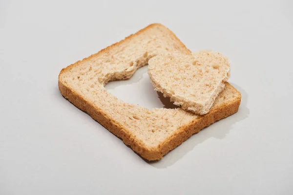 Slice of bread with carved heart shape on grey background — Stock Photo