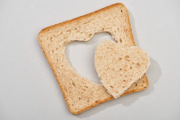 Top view of slice of bread with carved heart on grey background — Stock Photo
