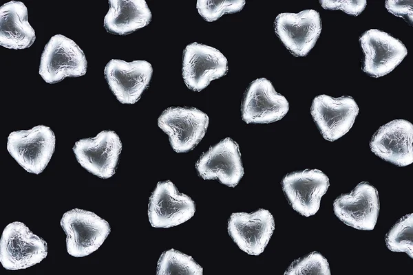 Vue du dessus des bonbons en feuille en forme de coeur isolé sur noir — Photo de stock
