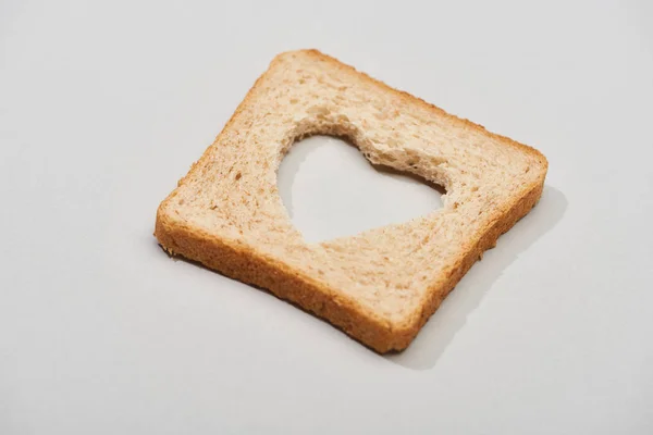 Bread slice with carved heart shape on grey background — Stock Photo
