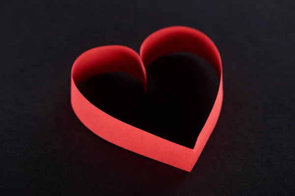 Red paper in heart shape isolated on black — Stock Photo