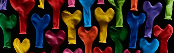 Top view of colorful heart shaped balloons isolated on black, panoramic shot — Stock Photo