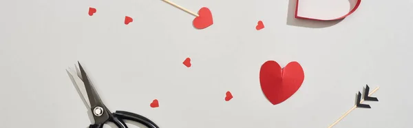 Top view of scissors, arrows and paper hearts on grey background, panoramic shot — Stock Photo