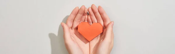 Top view of woman holding heart shaped paper on grey background, panoramic shot — Stock Photo