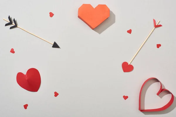 Vista dall'alto di carte a forma di cuore con frecce su sfondo grigio — Foto stock