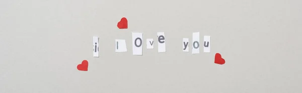 Top view of i love you lettering with heart shaped papers isolated on grey, panoramic shot — Stock Photo