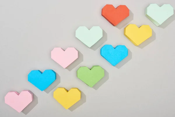 Вид зверху барвистих паперових сердець на сірому фоні — стокове фото