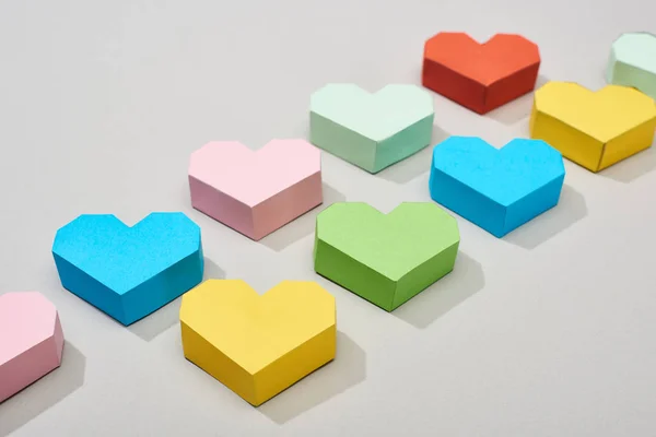Papéis decorativos coloridos em forma de coração em fundo cinza — Fotografia de Stock
