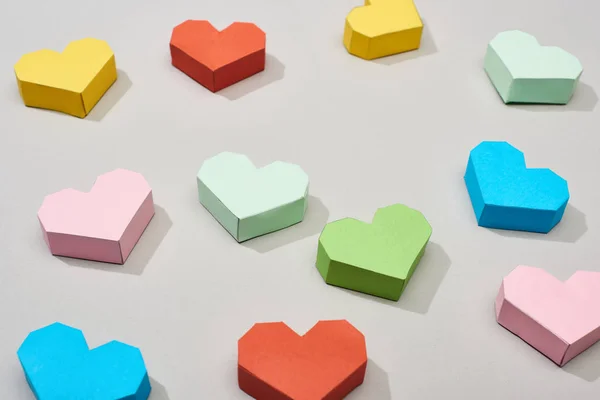 Papeles coloridos en forma de corazón sobre fondo gris - foto de stock