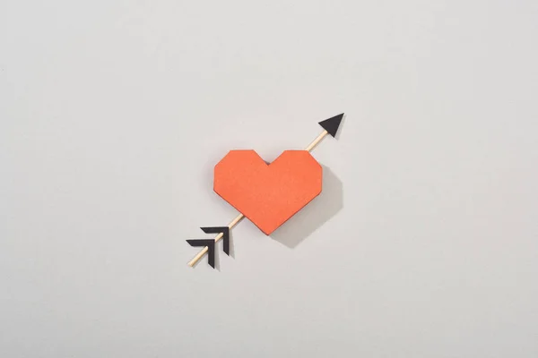Vista dall'alto del cuore decorativo di carta con freccia su sfondo grigio — Foto stock