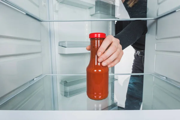 Abgeschnittene Ansicht einer Frau, die Tomatensauce aus dem Kühlschrank auf weißem Hintergrund nimmt — Stockfoto