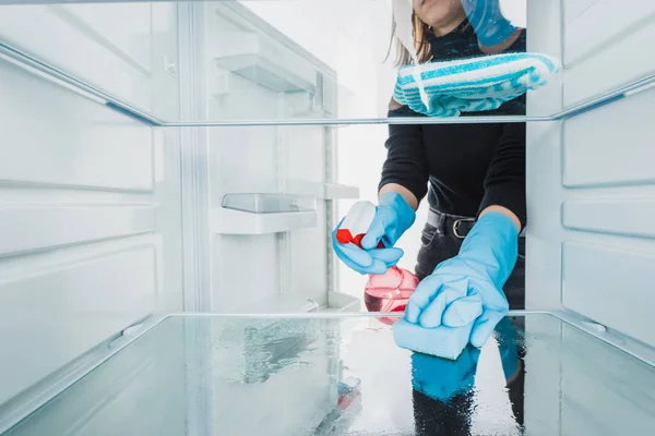Обрізаний вид жінки в гумових рукавичках прибирає холодильник з миючим засобом ізольовані на білому — стокове фото