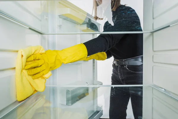 Vista recortada de mujer en guantes de goma limpiando refrigerador con trapo aislado en blanco - foto de stock