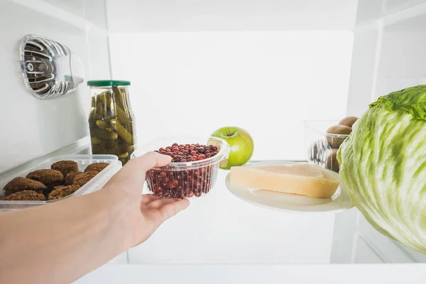Abgeschnittene Ansicht einer Frau, die frische Johannisbeeren aus dem Kühlschrank nimmt, mit Lebensmitteln isoliert auf weiß — Stockfoto
