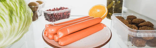 Panoramic shot of sausages, cutlets with cabbage and fruits in refrigerator isolated on white — Stock Photo