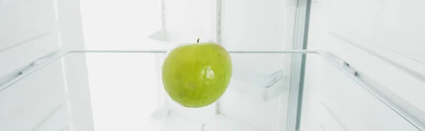 Свіже зелене яблуко в холодильнику з відкритими дверима ізольовано на білому — стокове фото