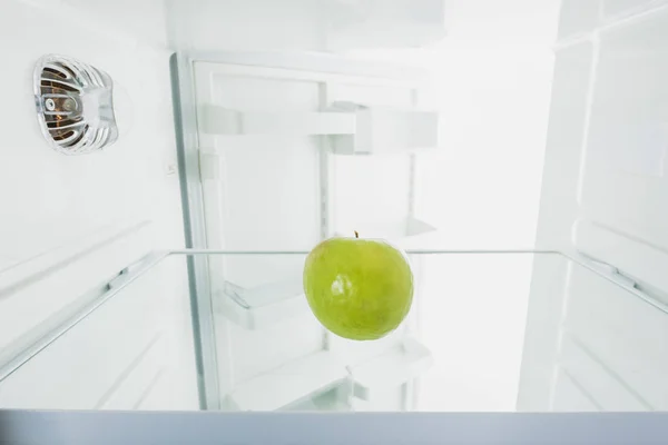 Manzana verde jugosa en nevera con puerta abierta aislada en blanco - foto de stock