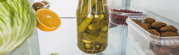 Panoramic shot of pickles with cutlets and fresh fruits on fridge shelf isolated on white — Stock Photo