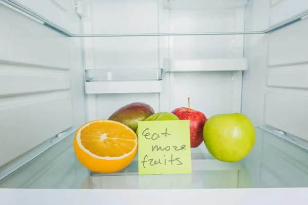 Card with eat more fruits lettering with fruits in refrigerator — Stock Photo