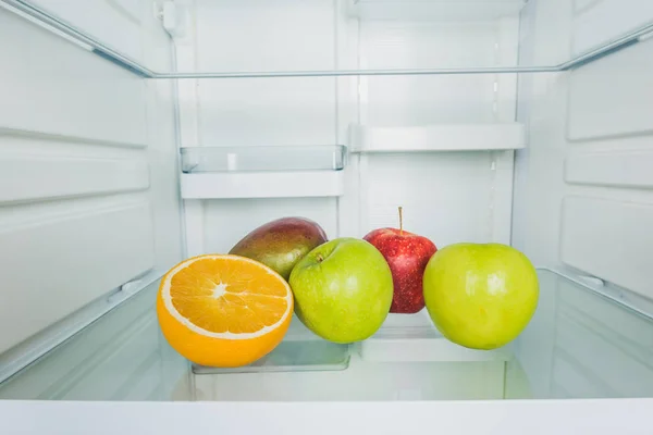 Fresh apples with mango and orange slice on fridge shelf — Stock Photo