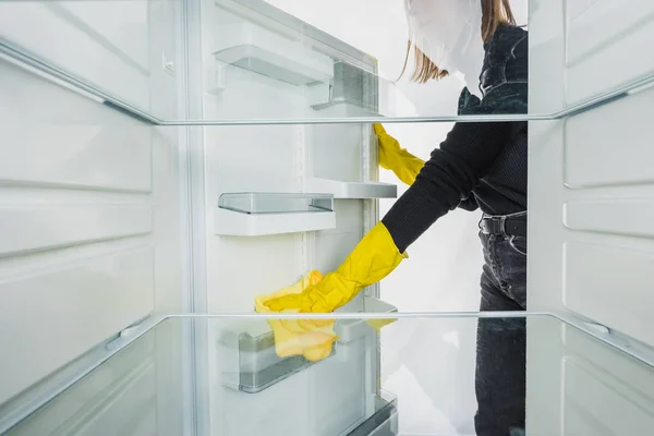 Vista recortada de las estanterías de limpieza de mujer en la puerta del refrigerador aislado en blanco - foto de stock