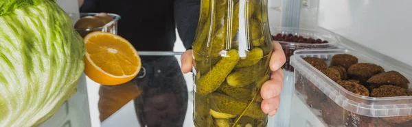 Vue recadrée de la femme prenant pot de cornichons du réfrigérateur avec de la nourriture sur fond blanc, vue panoramique — Photo de stock