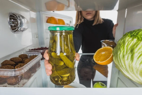 Cropped view of woman taking far with pickles from fridge shelf isolated on white — Stock Photo