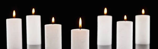 Enfoque selectivo de la quema de velas blancas que brillan aislados en negro, tiro panorámico - foto de stock