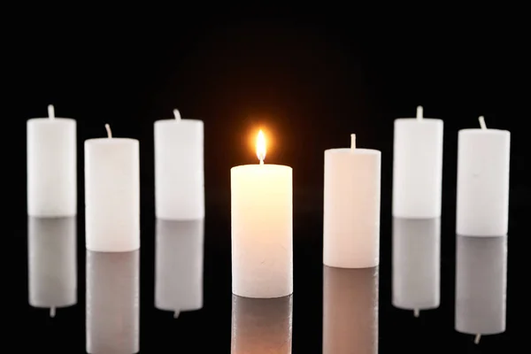 Foyer sélectif des bougies blanches allumées près d'un autre isolé sur noir — Photo de stock