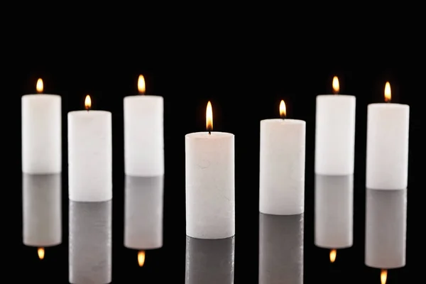 Selective focus of burning white candles glowing isolated on black — Stock Photo