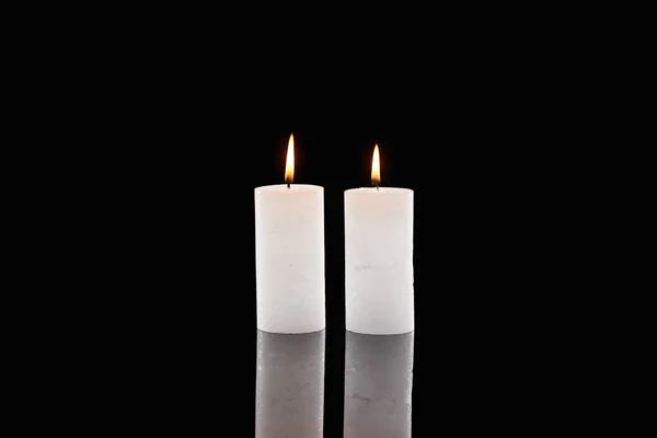 Dos velas blancas ardientes que brillan aisladas en negro - foto de stock